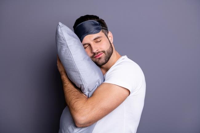 אילסוטרציה: גבר מחבק כרית ועוצם את עיניו, מדמה שינה עמוקה ואיכותית